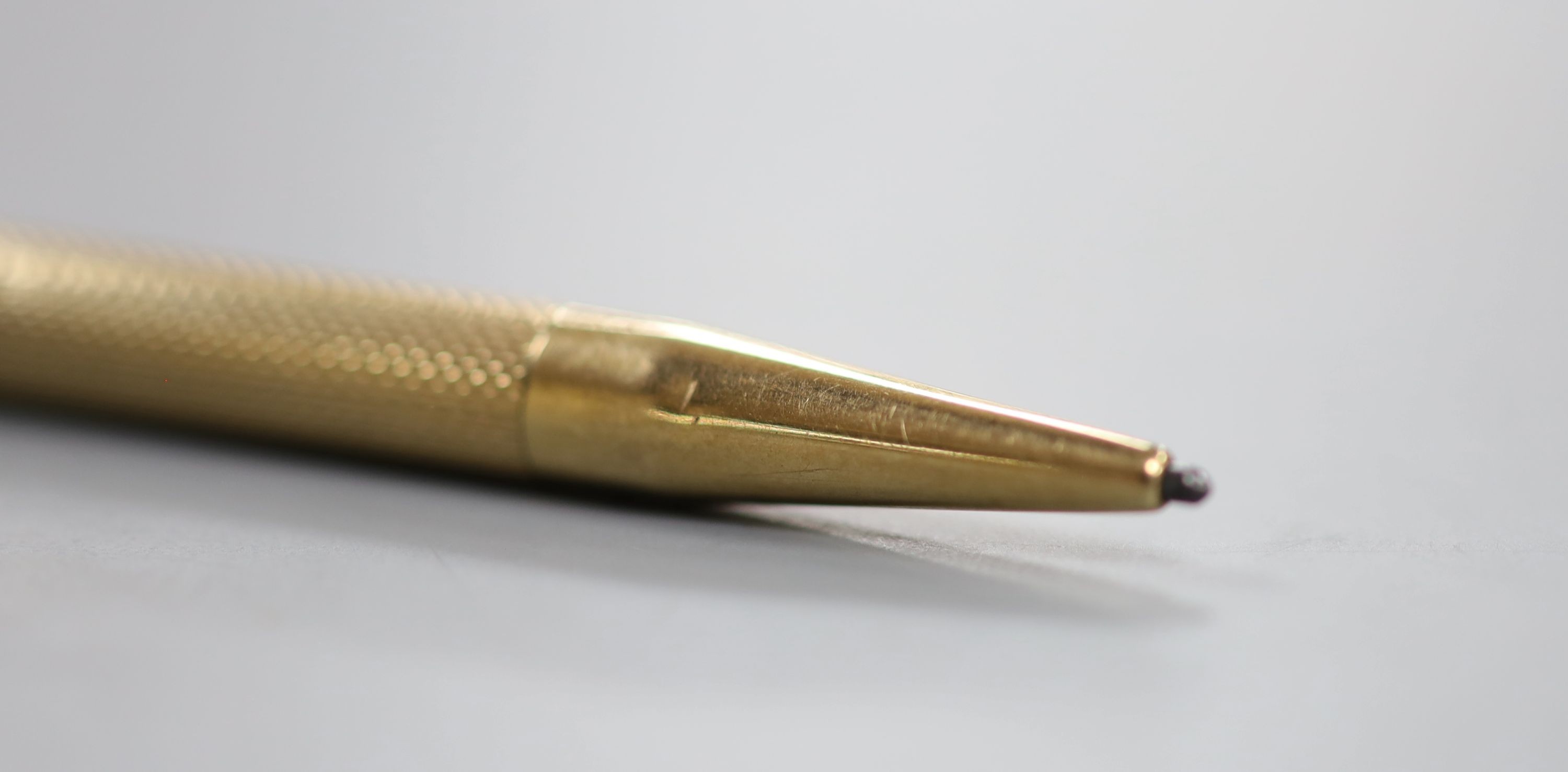 An engine turned 9ct gold cased pencil, 86mm, gross weight 10.5 grams.